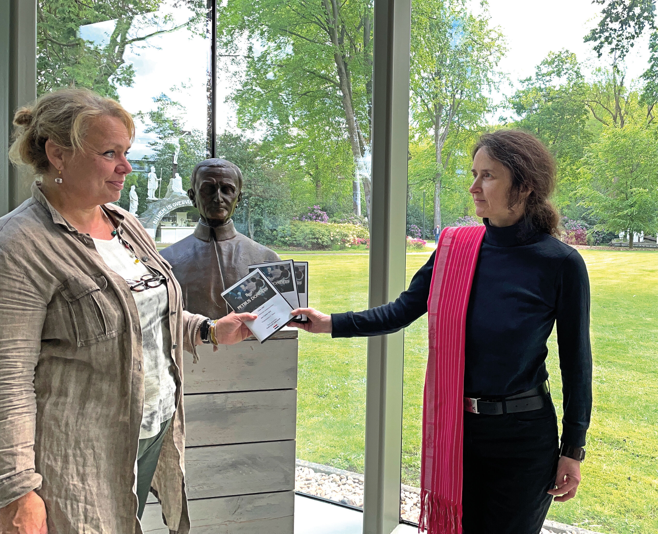 Vicepostulator Claudia Peters (rechts) overhandigt aan Esther Becx, coördinator van het Peerke Donderspaviljoen, exemplaren van een film over Petrus Donders.